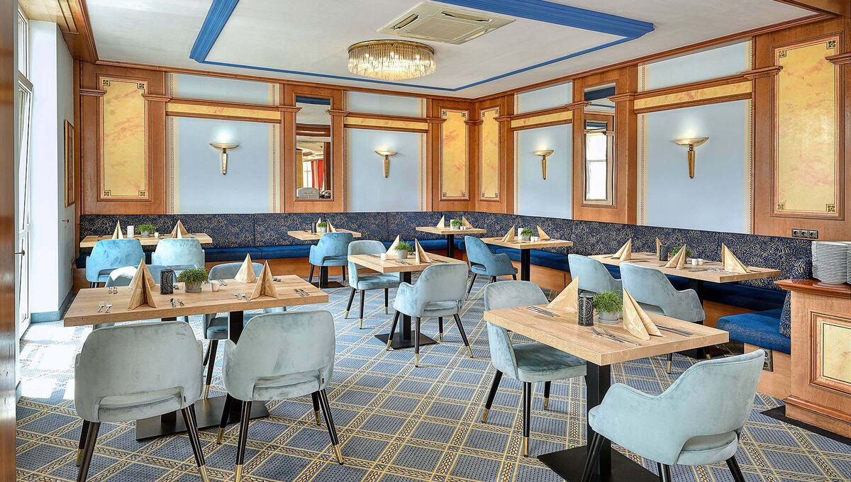 Restaurantbereich in verschiedenen Blautönen mit Samtstühlen an den hellen Holztischen 