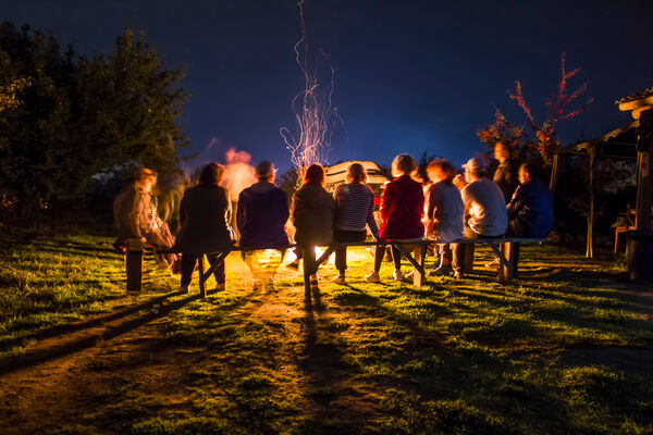 Am Abend sitzt eine Gruppe an einem Lagerfeuer während des Rahmenprogramms der Tagung  