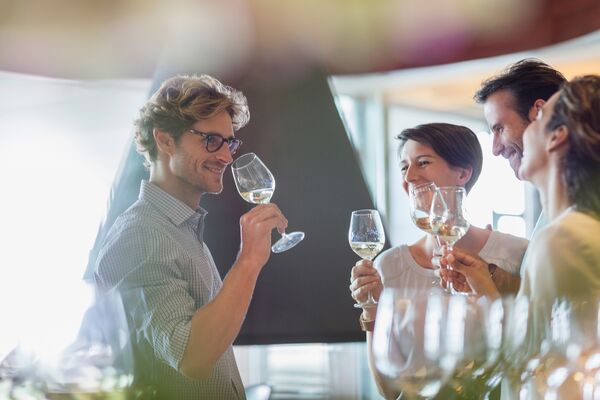 Vier Personen trinken gemeinsam Weißwein beim Rahmenprogramm der Tagung 