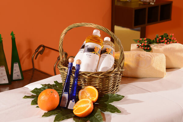Gedeckter Tisch im Wellness Bereich mit Orangen, Massageöl und Handtüchern.
