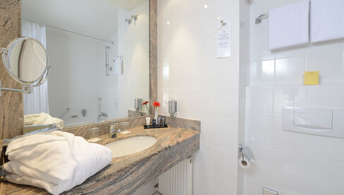 Waschbecken mit Natursteinmuster mit Handtuch im Bad mit großem Spiegel