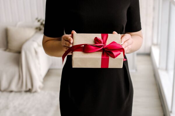 Frau in schwarzem Kleid hält ein Geschenk mit roter Schleife im Hotel in Bad Gögging